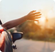 A passenger holds their hand out of an open car window. 